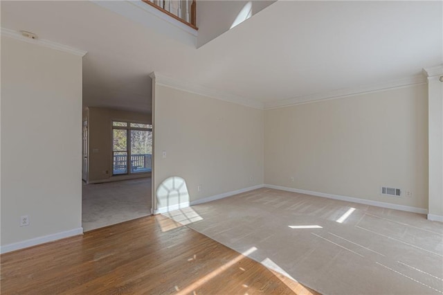 unfurnished living room featuring light wood finished floors, baseboards, visible vents, and ornamental molding