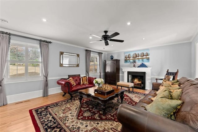 living area with ornamental molding, wood finished floors, visible vents, and a healthy amount of sunlight