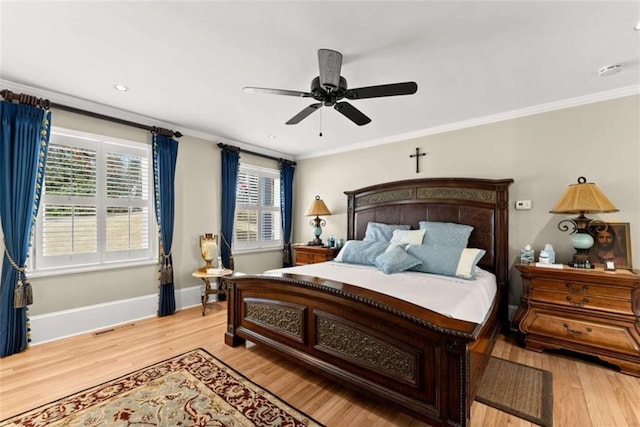 bedroom with baseboards, crown molding, visible vents, and light wood finished floors