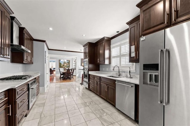 kitchen featuring stainless steel appliances, a sink, a healthy amount of sunlight, light countertops, and ornamental molding