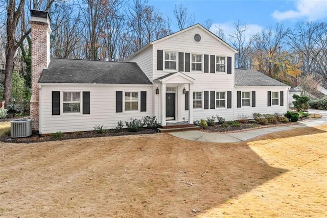 view of front of home featuring a chimney, a front lawn, and cooling unit