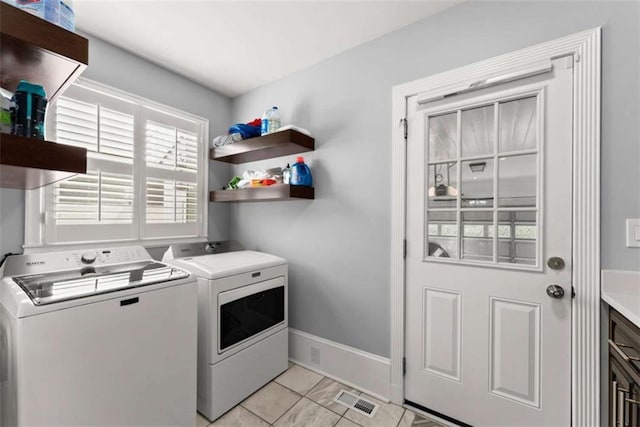 laundry area with light tile patterned floors, visible vents, washer and dryer, laundry area, and baseboards