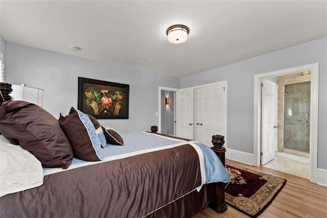 bedroom with a closet, baseboards, ensuite bath, and light wood finished floors