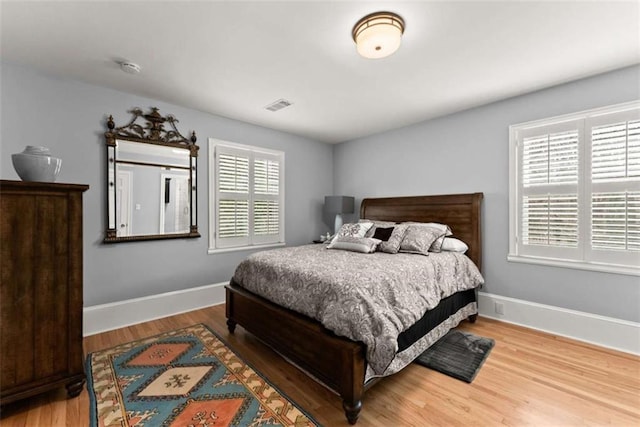 bedroom featuring baseboards, visible vents, and wood finished floors