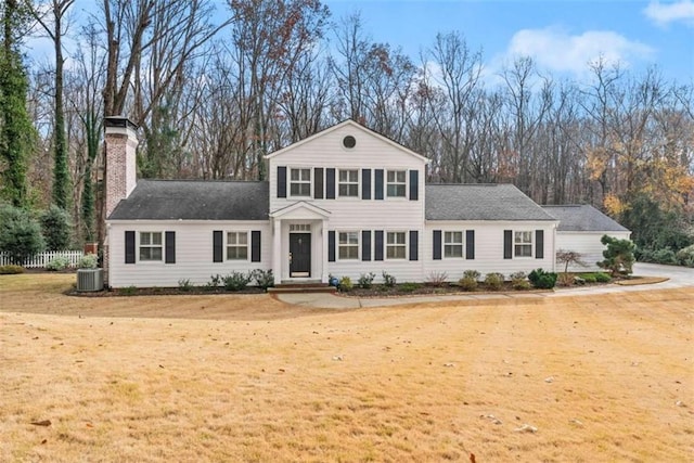 view of front of home featuring central AC, a chimney, and a front lawn