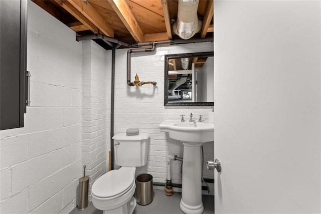 half bathroom with finished concrete flooring, toilet, and concrete block wall