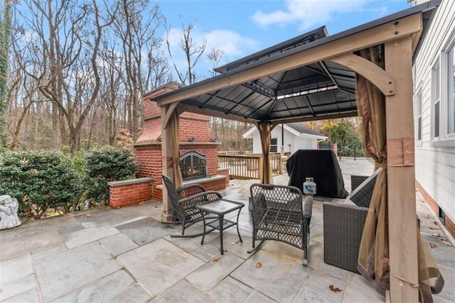 view of patio / terrace featuring area for grilling, a gazebo, and an outdoor living space with a fireplace