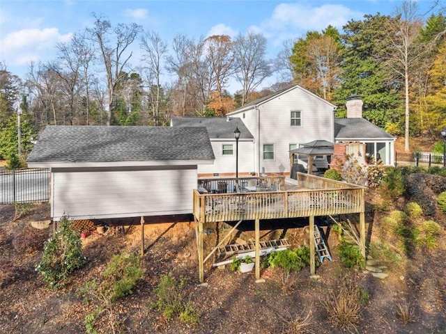 rear view of house with a gazebo, roof with shingles, fence, and a wooden deck