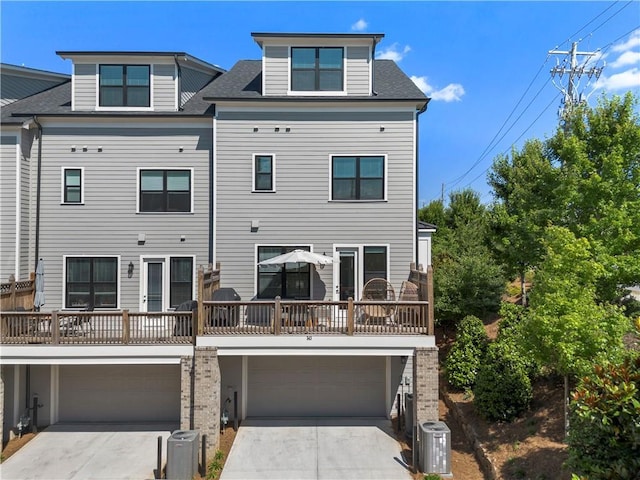 view of front of home featuring concrete driveway, cooling unit, an attached garage, and a shingled roof