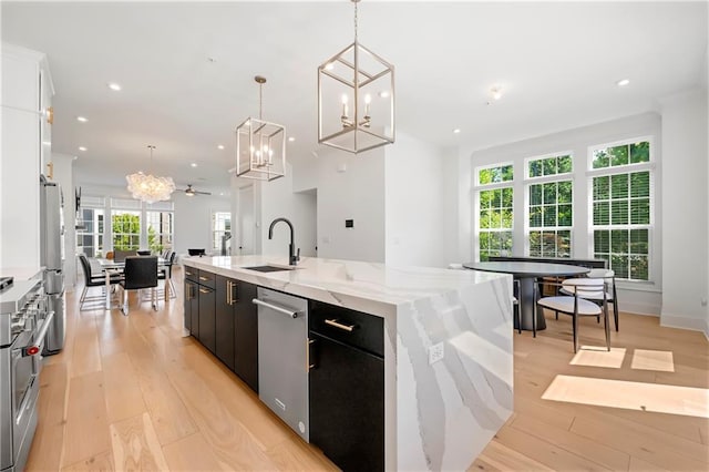 kitchen featuring light wood-style flooring, a sink, a spacious island, open floor plan, and appliances with stainless steel finishes