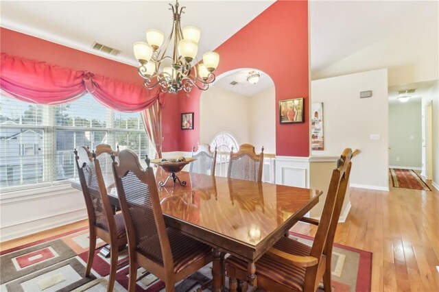 dining room featuring high vaulted ceiling, wood-type flooring, and an inviting chandelier