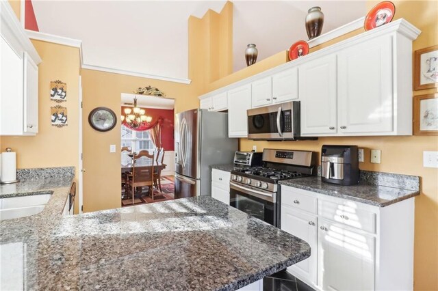 kitchen featuring kitchen peninsula, white cabinetry, stainless steel appliances, dark stone countertops, and a notable chandelier