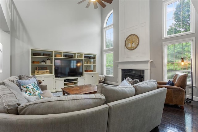141 Ennisbrook Dr SE, Smyrna, GA 30082 - living area featuring a towering ceiling, a ceiling fan, dark wood-style flooring, a fireplace, and baseboards