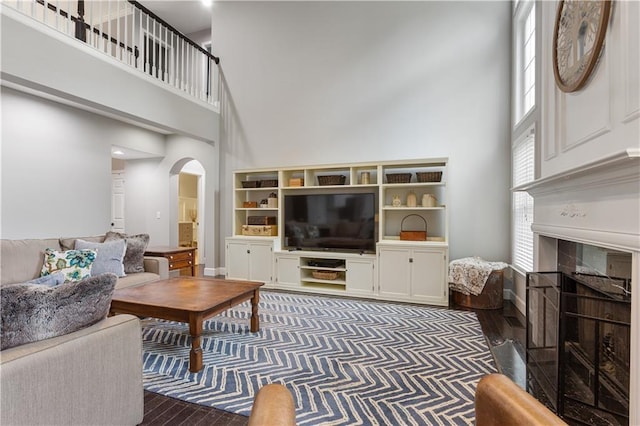 141 Ennisbrook Dr SE, Smyrna, GA 30082 - living area with arched walkways, a high ceiling, a tiled fireplace, and wood finished floors