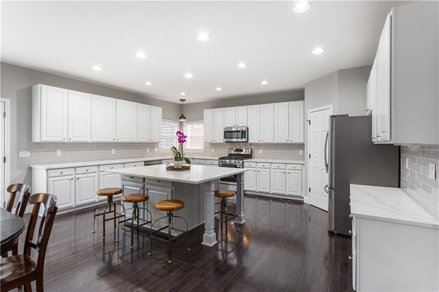 141 Ennisbrook Dr SE, Smyrna, GA 30082 - kitchen featuring appliances with stainless steel finishes, decorative backsplash, a kitchen breakfast bar, white cabinetry, and a kitchen island