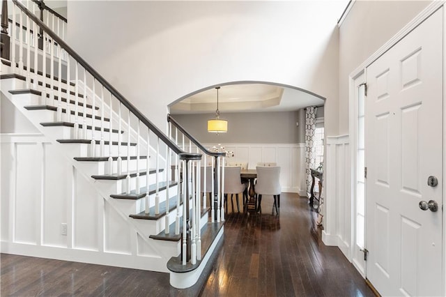 141 Ennisbrook Dr SE, Smyrna, GA 30082 - foyer featuring arched walkways, dark wood-style floors, wainscoting, stairway, and a decorative wall