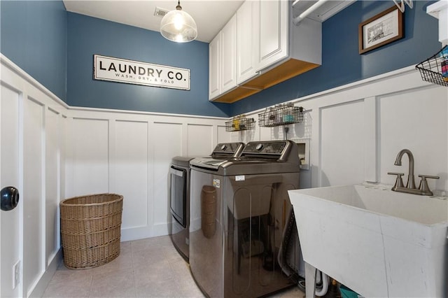 141 Ennisbrook Dr SE, Smyrna, GA 30082 - laundry area with cabinet space, a decorative wall, washer and clothes dryer, a wainscoted wall, and light tile patterned flooring