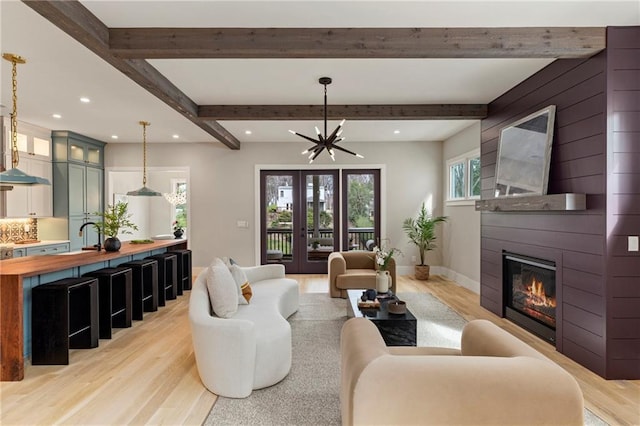 living room with light wood-type flooring, beamed ceiling, and baseboards