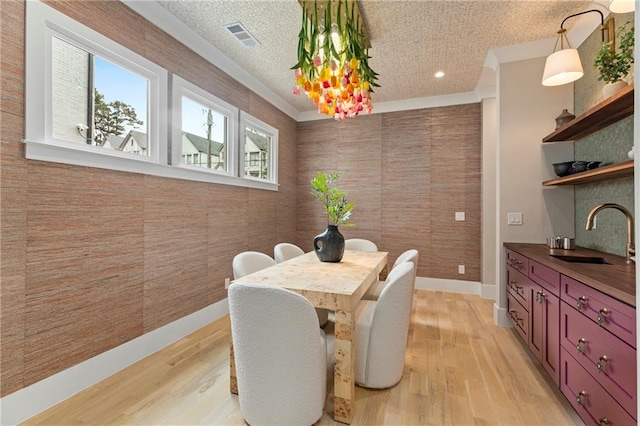 dining room with baseboards, visible vents, a textured ceiling, and light wood finished floors