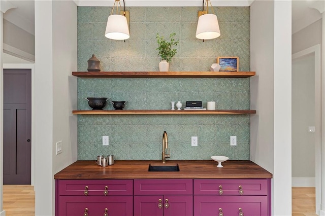 kitchen featuring open shelves, wooden counters, decorative backsplash, light wood-style floors, and a sink