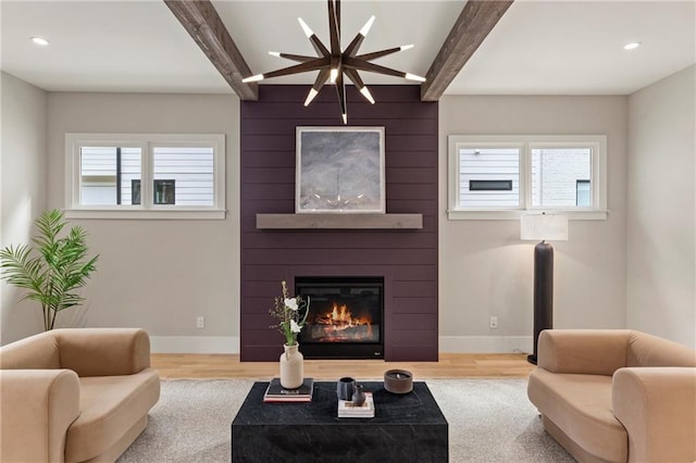 living area with beamed ceiling, plenty of natural light, baseboards, and a large fireplace