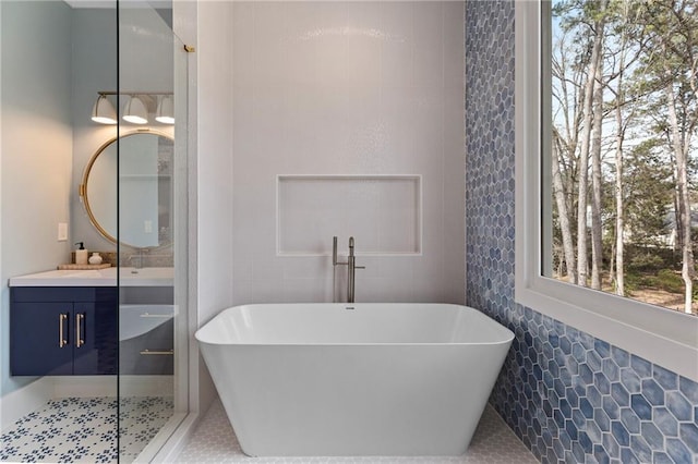 full bathroom featuring a freestanding tub, tile walls, and vanity