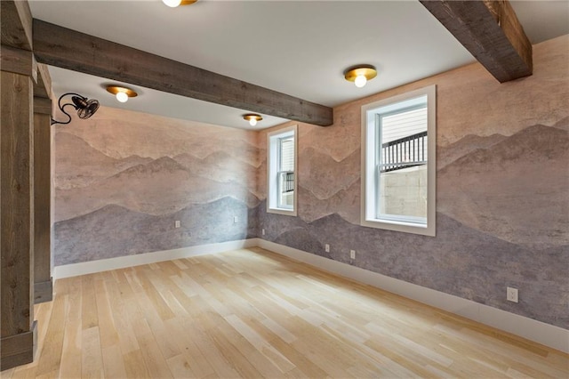 unfurnished room featuring baseboards, beamed ceiling, and wood finished floors