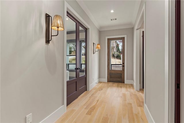 doorway with light wood finished floors, baseboards, visible vents, ornamental molding, and recessed lighting