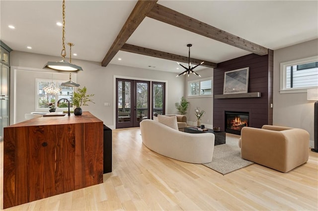 living area with recessed lighting, a large fireplace, light wood-style floors, beamed ceiling, and an inviting chandelier