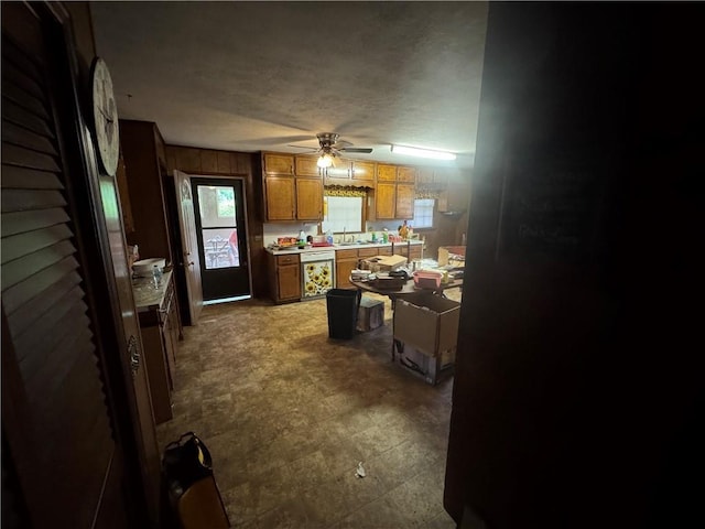 kitchen featuring brown cabinets, a ceiling fan, light countertops, and dishwashing machine