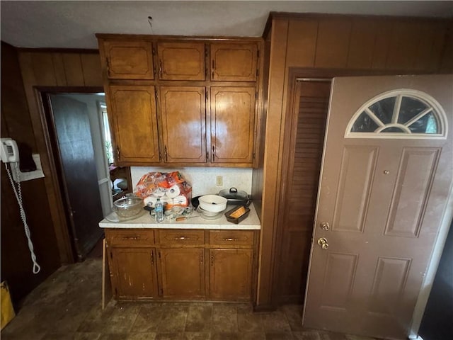 kitchen featuring brown cabinetry, light countertops, and wooden walls