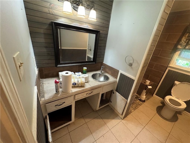 bathroom featuring tile patterned floors, toilet, vanity, and wooden walls