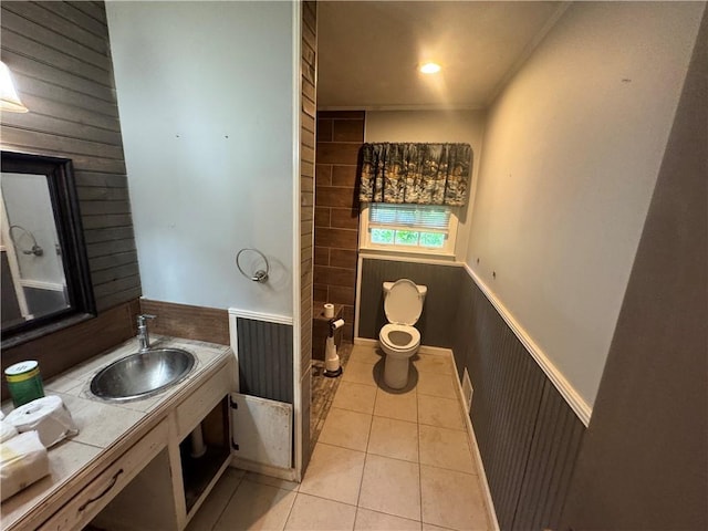 bathroom featuring a wainscoted wall, toilet, tile patterned floors, wood walls, and vanity