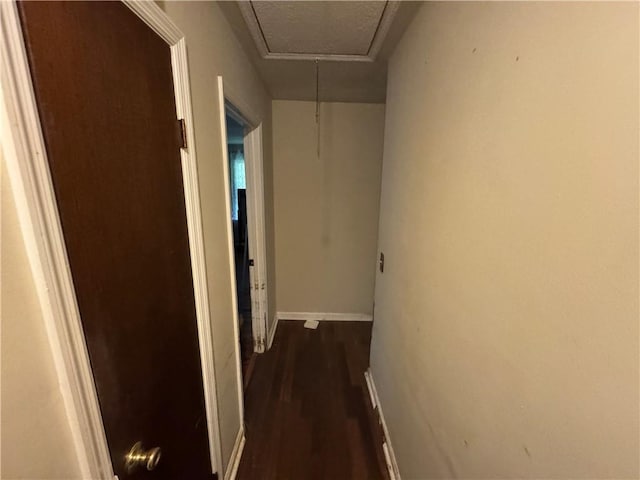 corridor with attic access, dark wood finished floors, and baseboards