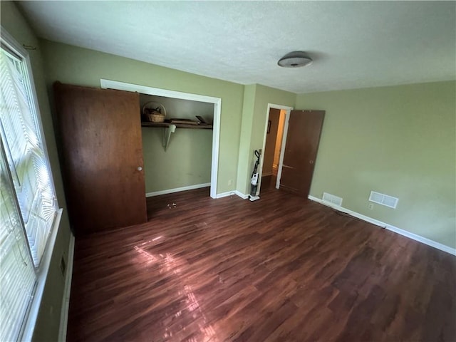 unfurnished bedroom featuring wood finished floors, baseboards, a closet, and a textured ceiling