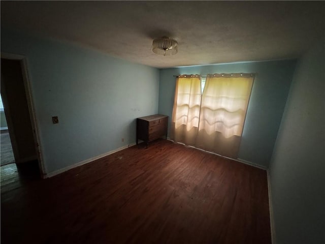 unfurnished room with wood finished floors, healthy amount of natural light, and baseboards