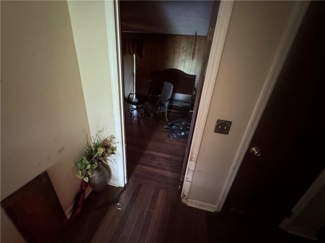corridor featuring wood finished floors and wooden walls