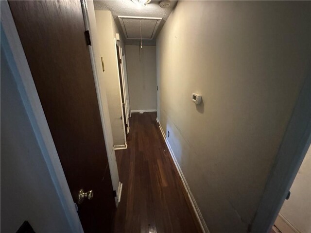 corridor with attic access, dark wood finished floors, and baseboards