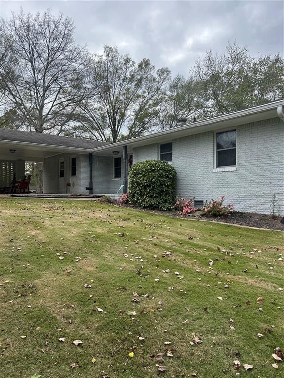 exterior space with a carport, crawl space, brick siding, and a front yard