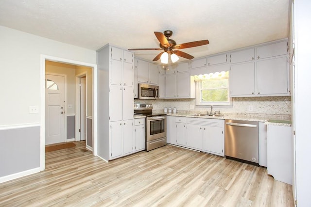 kitchen featuring sink, light hardwood / wood-style floors, decorative backsplash, and stainless steel appliances