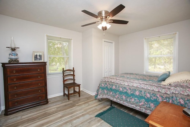 bedroom with light wood finished floors, a closet, baseboards, and a ceiling fan