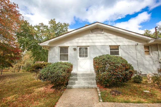 bungalow-style home with a front lawn, brick siding, and crawl space