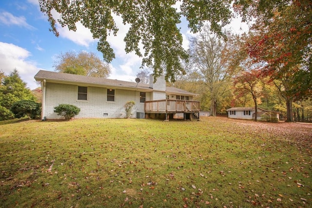 back of property with brick siding, a lawn, a deck, an outdoor structure, and crawl space