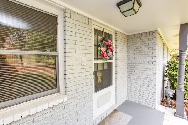 entrance to property with brick siding and covered porch