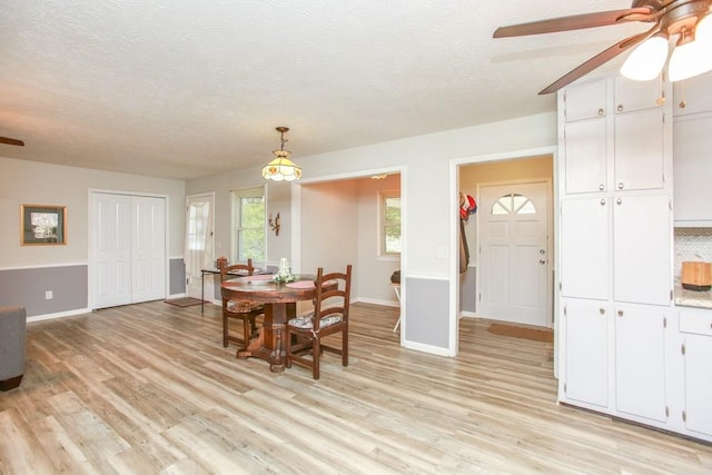 dining room featuring light wood-type flooring, a textured ceiling, and ceiling fan