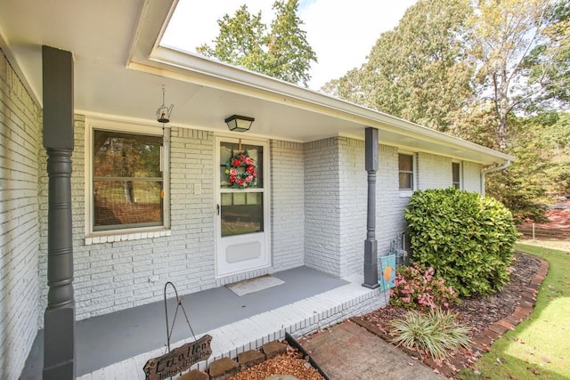 property entrance with brick siding and a porch