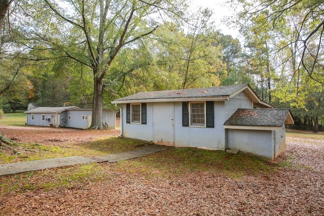 view of front of home featuring concrete block siding, a wooded view, and roof with shingles