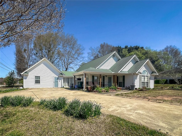 view of front facade with a porch, concrete driveway, and metal roof
