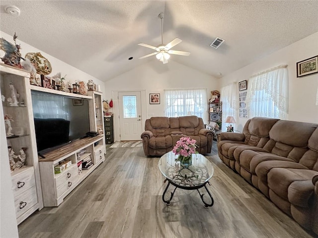 living area with wood finished floors, ceiling fan, a textured ceiling, and vaulted ceiling