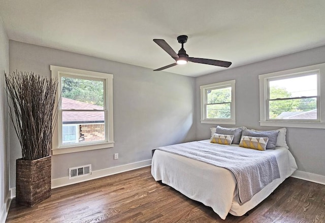 bedroom featuring baseboards, visible vents, dark wood-style flooring, and multiple windows